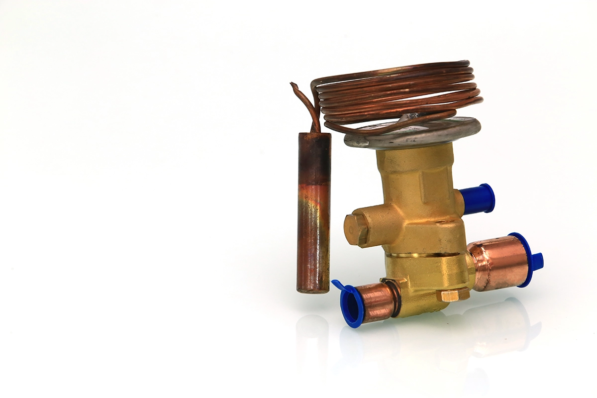 Close-up of a thermostatic expansion valve with sensing bulb and copper coil tubing.