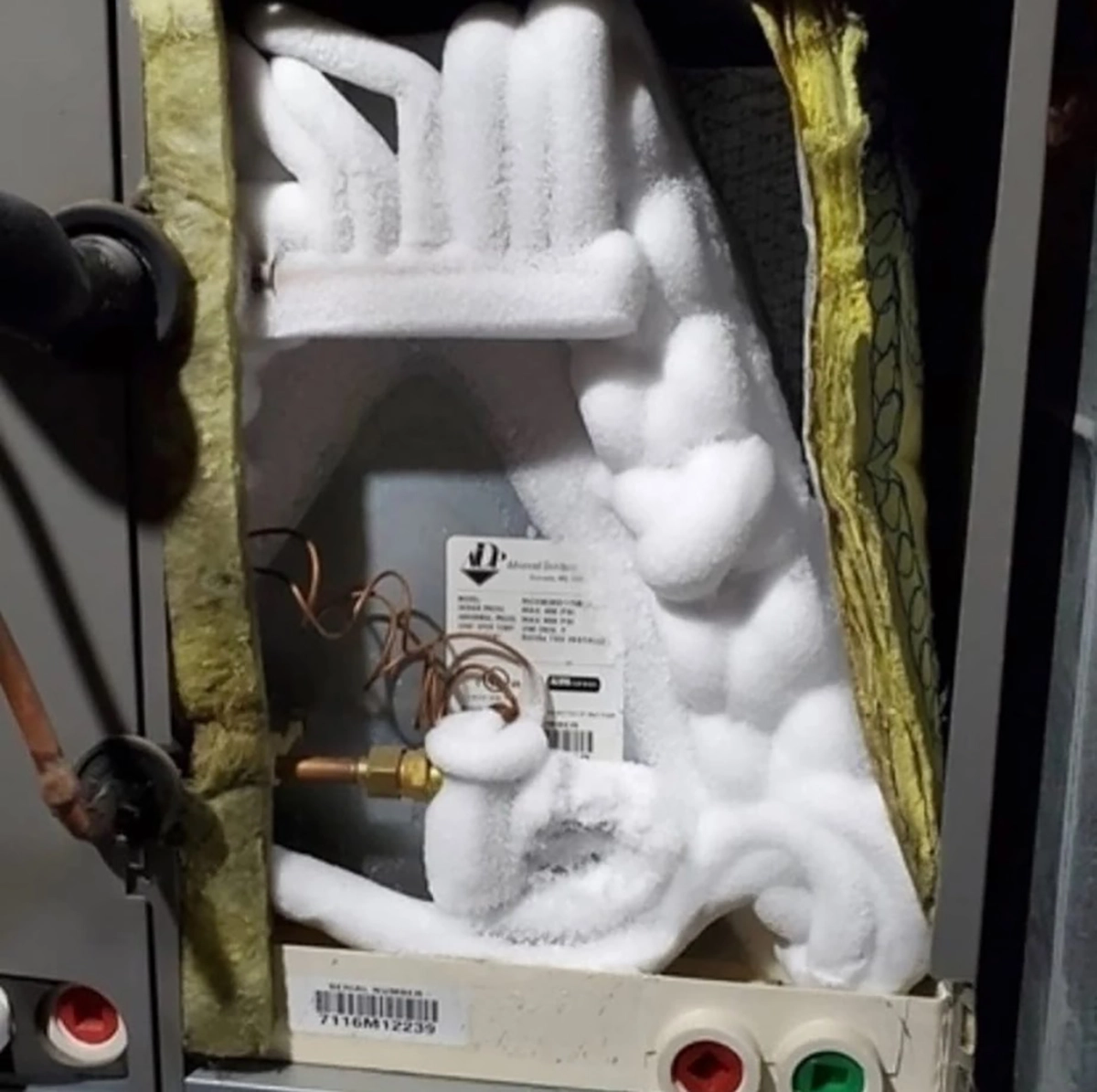 Close-up of ice buildup on indoor HVAC components and refrigerant lines inside an air handler or evaporator coil compartment. Best for blogs about frozen AC coils, evaporator coil freezing, AC not cooling, airflow problems, refrigerant issues, frozen HVAC unit troubleshooting.