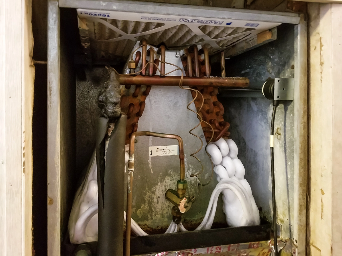 Frozen indoor evaporator coil with visible ice buildup inside an HVAC air handler.